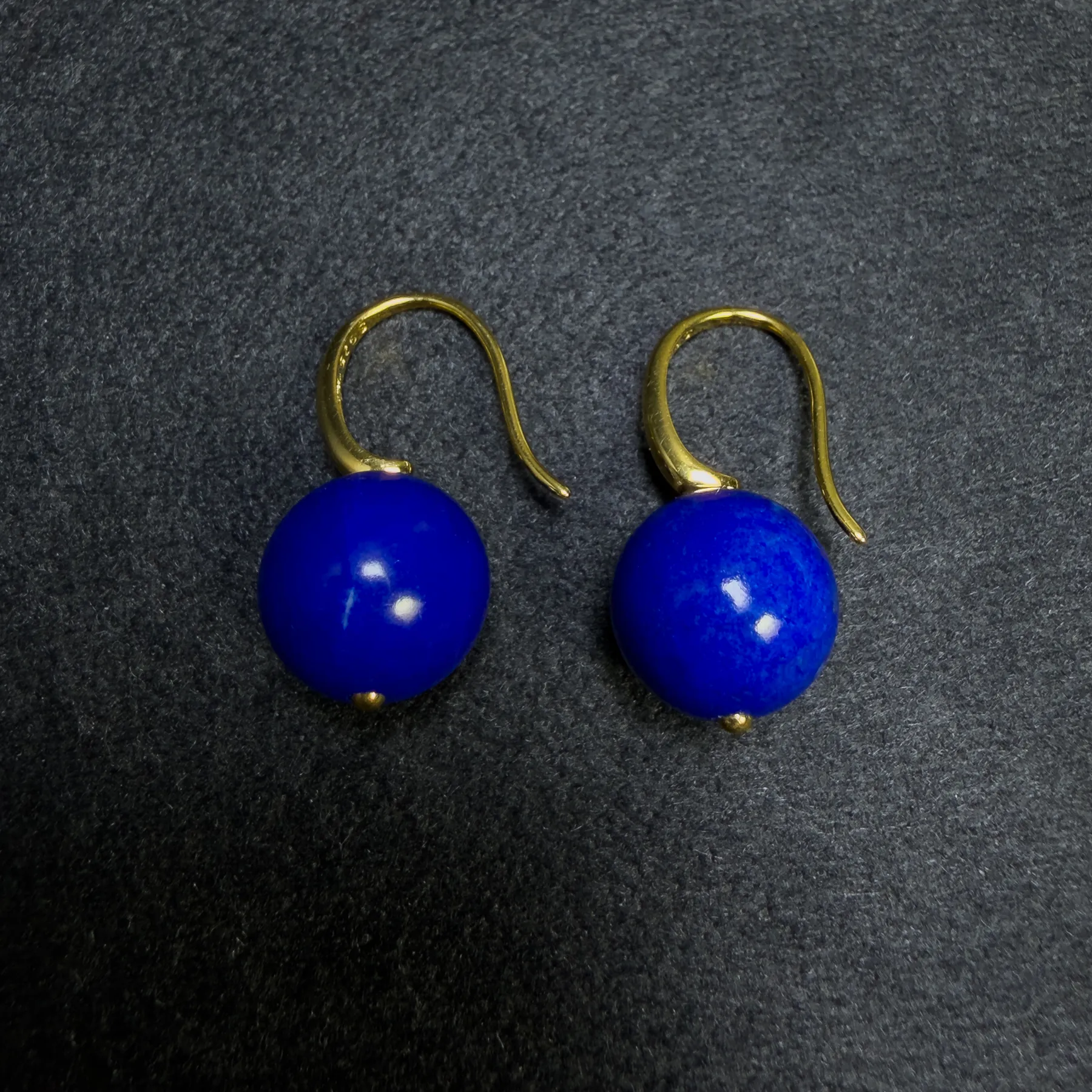 Close view of two deep-blue Afghan lapis lazuli round bead earrings