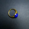 Side profile of a polished blue cabochon in a gold-tone ring