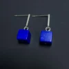 Close view of two blue cube earrings with silver articulated links