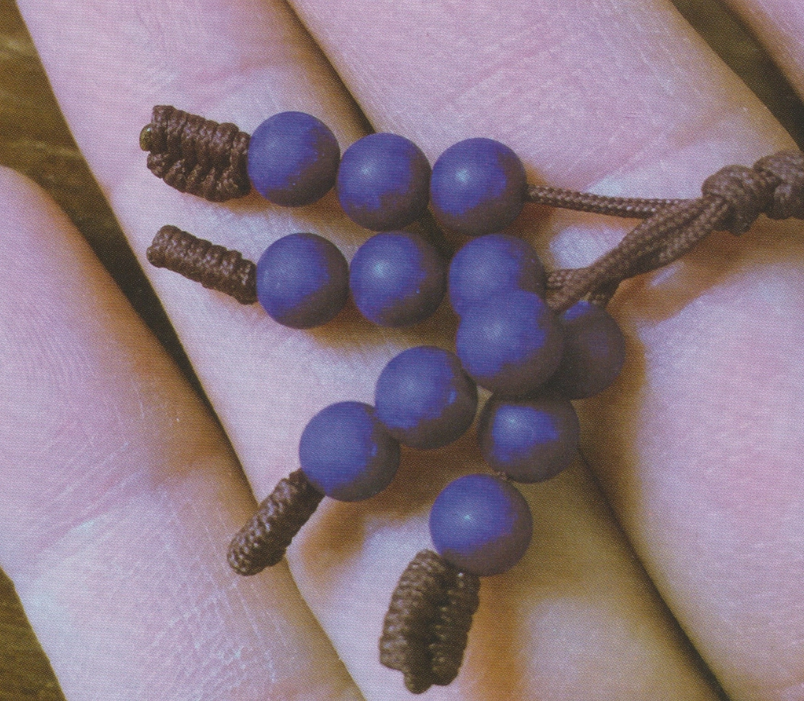 Blue lapis beads on brown knotted cords held in one hand