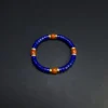 Wide view of blue and orange gemstone bracelet on a dark background
