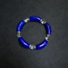 Curved lapis lazuli and clear quartz bracelet arranged on a dark background