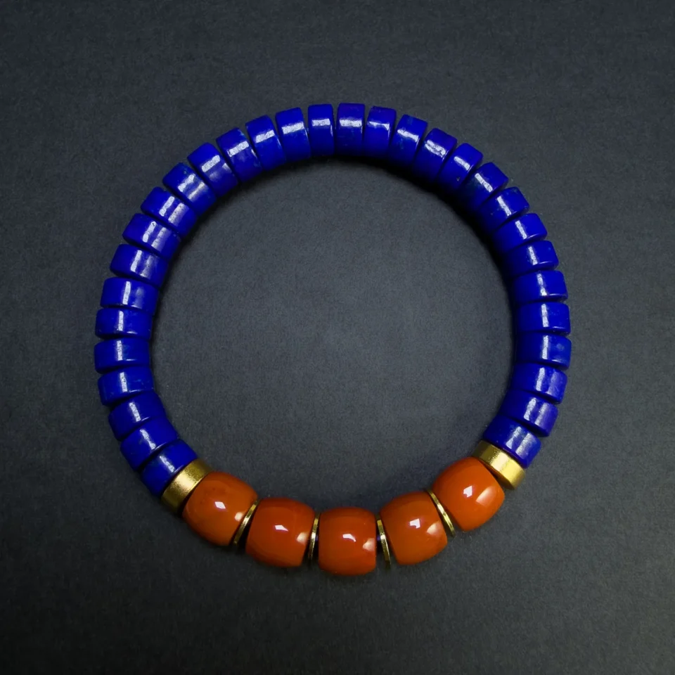 Close top view of five red agate beads beside blue lapis discs