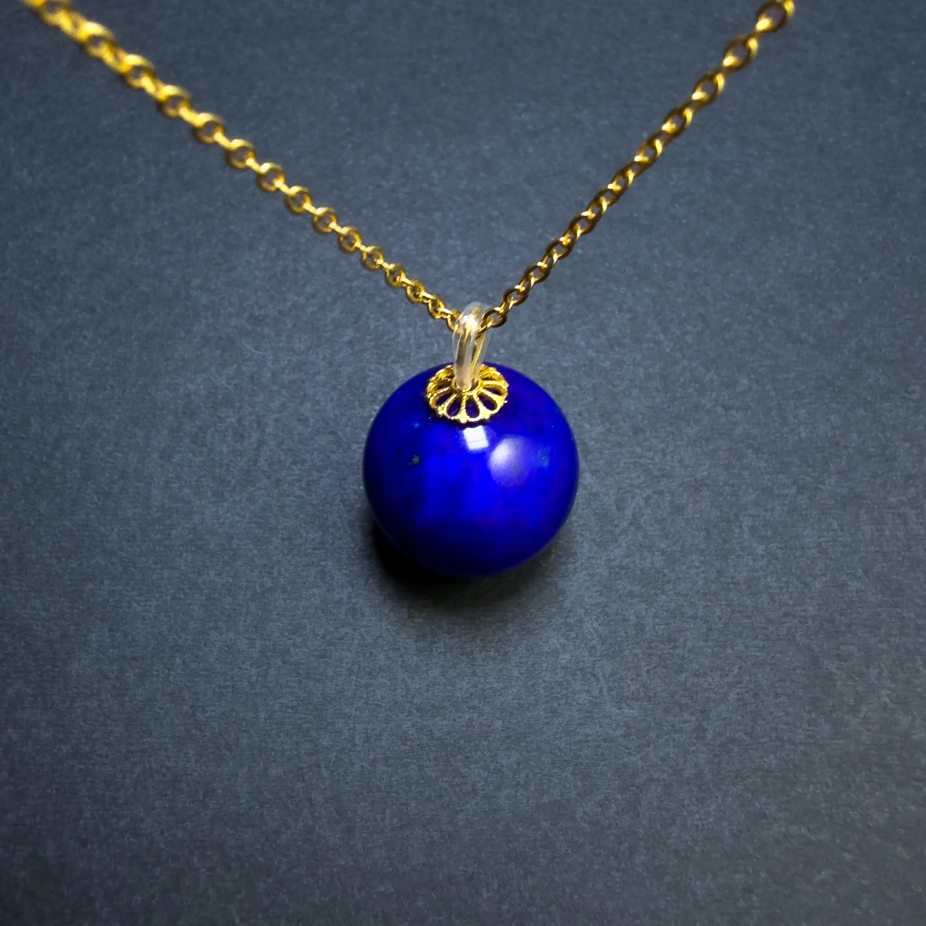Close view of imperial-blue lapis pendant with decorative gold-tone bead cap