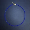 Full view of a vivid blue faceted lapis lazuli bead necklace with gold accents