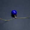 Side view of round lapis bead pendant with curved bail and chain
