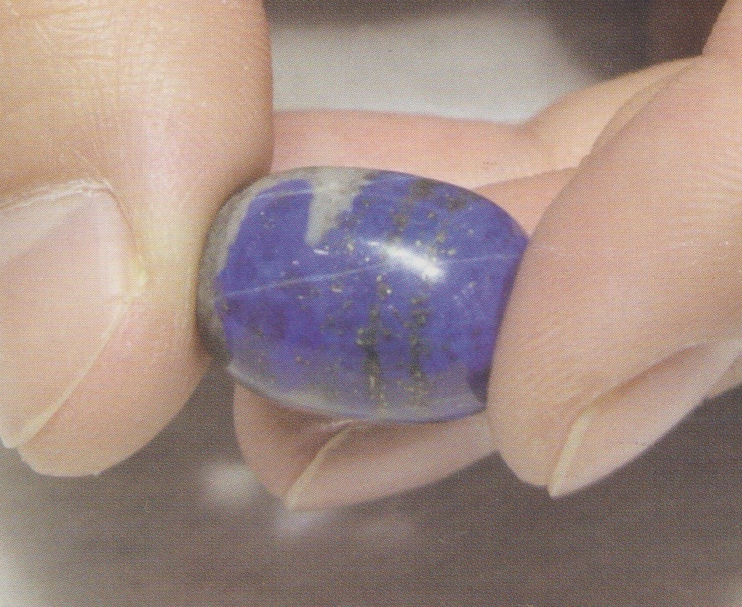 Polished blue bead with a pale patch and prominent surface line