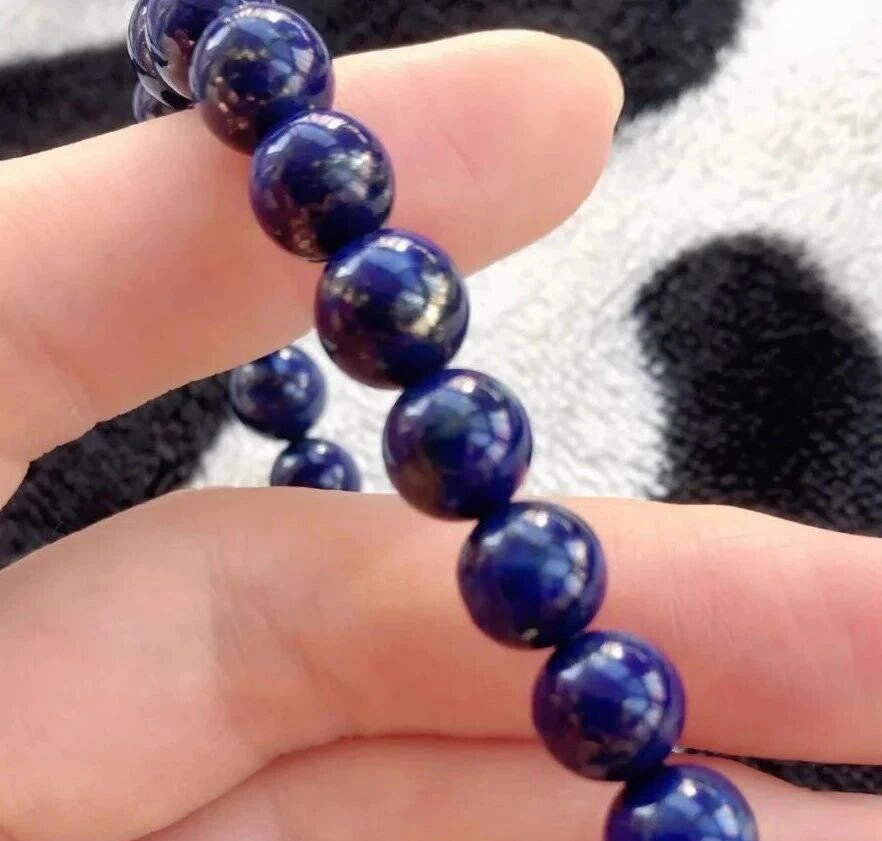 Round dark blue lapis bracelet beads held between fingers