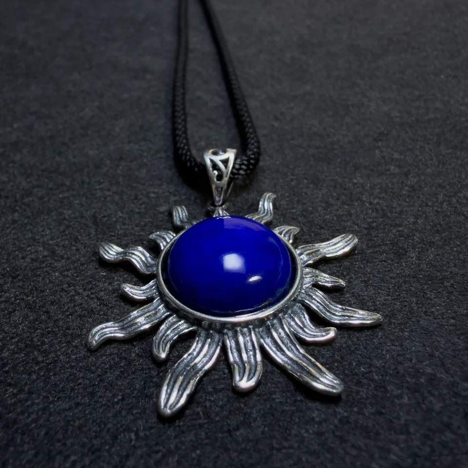 Close angled view of polished lapis lazuli cabochon and silver sun rays
