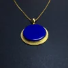 Angled close-up of blue lapis lazuli disc in textured gold-plated setting