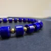 Close-up of deep-blue lapis barrel beads separated by polished gold-tone round beads