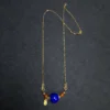 Full gold-tone chain with lapis lazuli orbit pendant on dark fabric