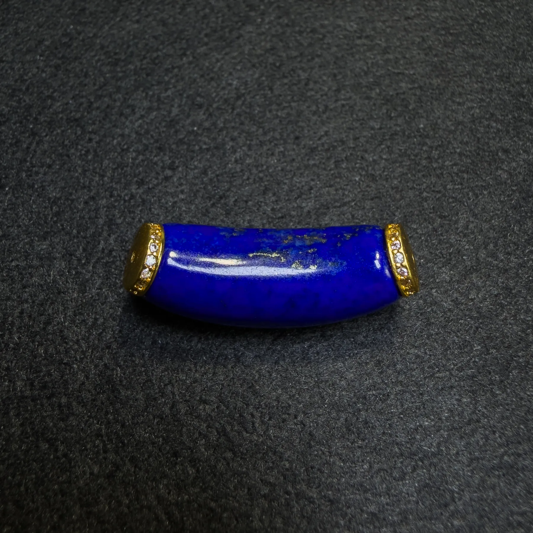 Close-up of a curved lapis lazuli component with natural pyrite flecks and gold-plated spacer details