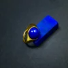 Gold-tone lapis lazuli ring resting on a blue jewelry display