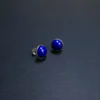Angled lapis lazuli studs with one clear earring back visible