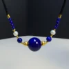 Close view of large round lapis bead with pearl and gold-tone accents