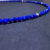 Macro detail of tiny faceted lapis lazuli beads beside one gold spacer bead