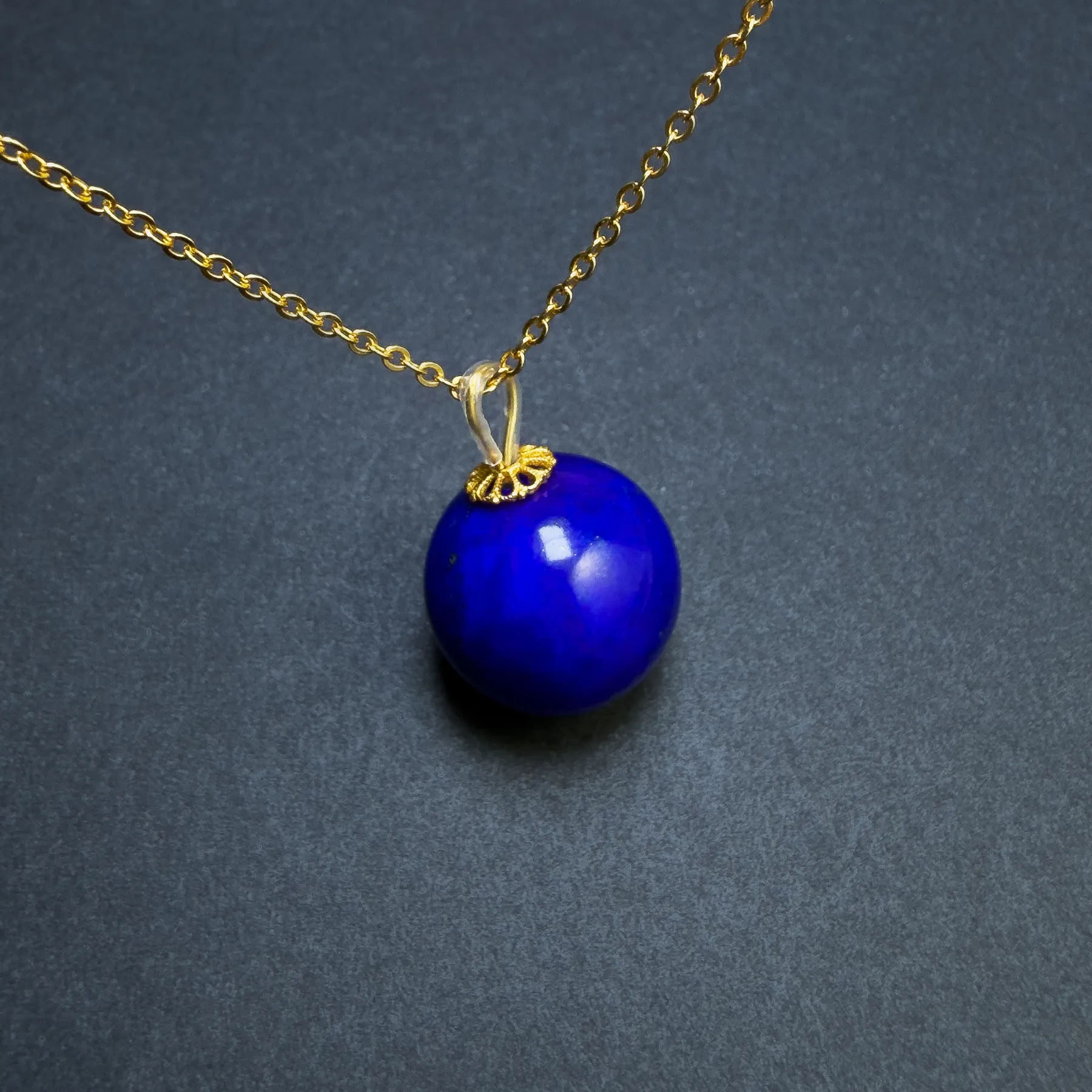 Minimalist round lapis lazuli pendant viewed at a close diagonal angle