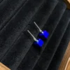 Minimal blue cube earrings resting inside a dark jewelry display box