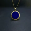 Minimalist round blue lapis pendant suspended above a dark surface