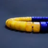 Close-up of natural honey-yellow amber disc beads beside blue lapis