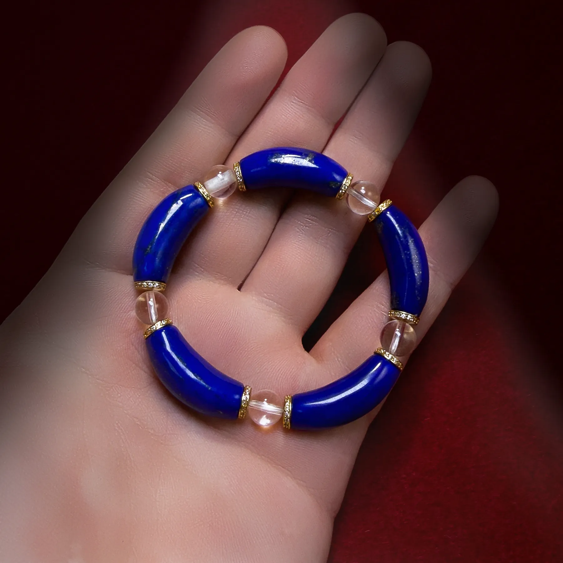 Natural lapis lazuli and clear quartz curved bead bracelet held in a hand