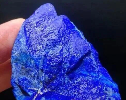 Rough blue lapis lazuli rock held between fingers