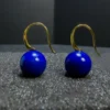 Close hook detail above round blue lapis lazuli drop earrings