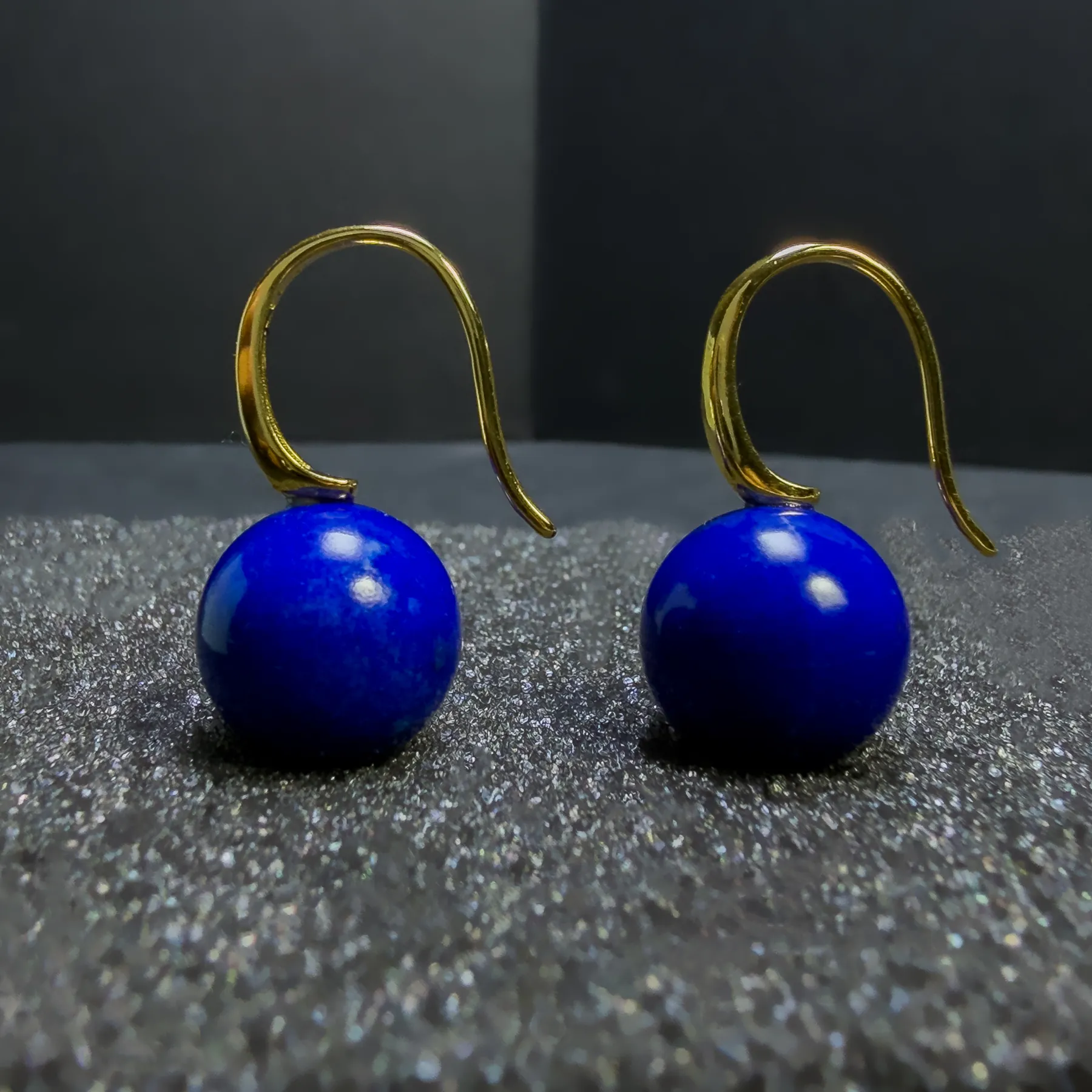 Close hook detail above round blue lapis lazuli drop earrings