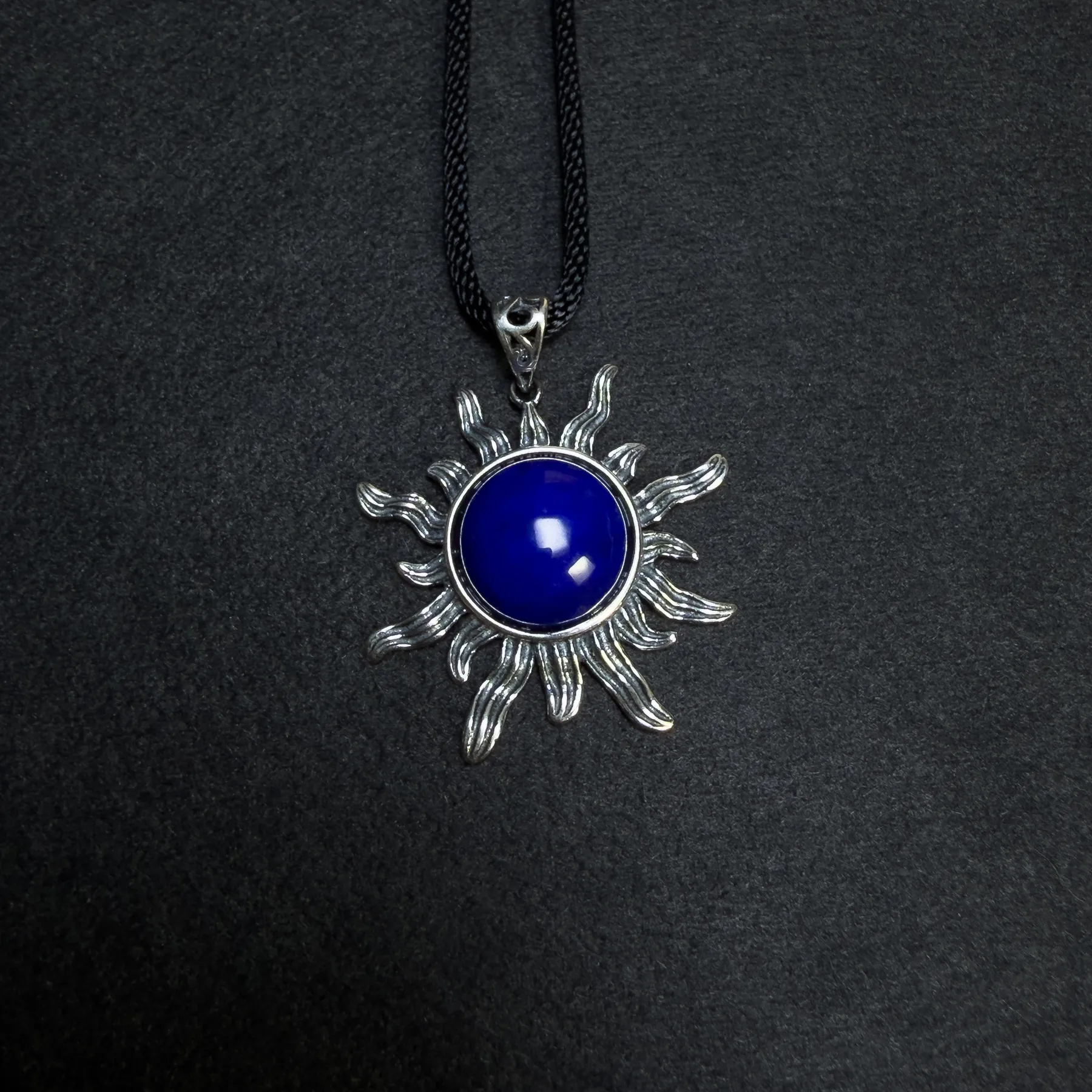 Round blue lapis lazuli cabochon centered in a silver sun pendant