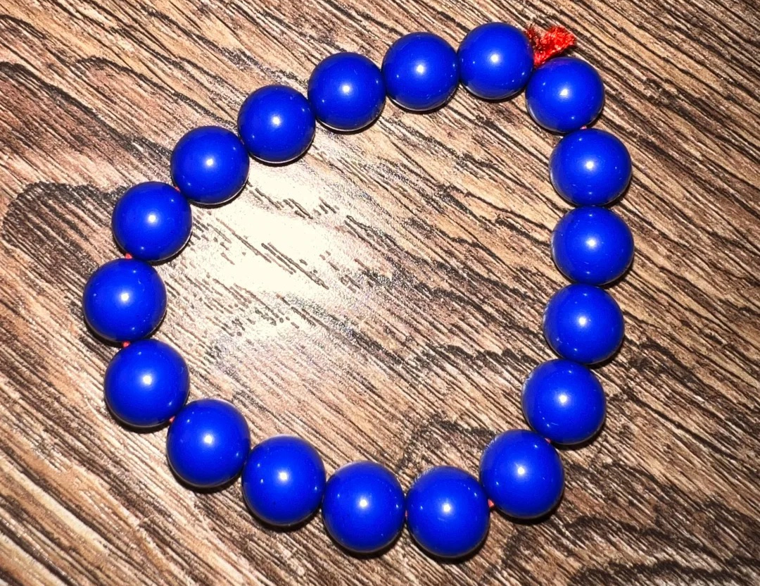 Circular bracelet of polished round blue lapis lazuli beads on wood