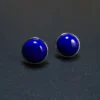 Angled front view of two round blue lapis studs with polished silver borders