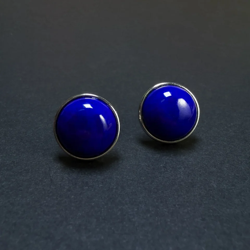 Angled front view of two round blue lapis studs with polished silver borders