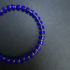 Angled overhead detail of royal-blue barrel beads with repeating gold-tone spacers