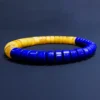 Low-angle view of royal-blue lapis disc beads with amber behind