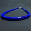 Angled detail of royal-blue lapis lazuli necklace curving across black surface