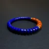 Side angle of royal-blue lapis bracelet with clustered orange-red beads