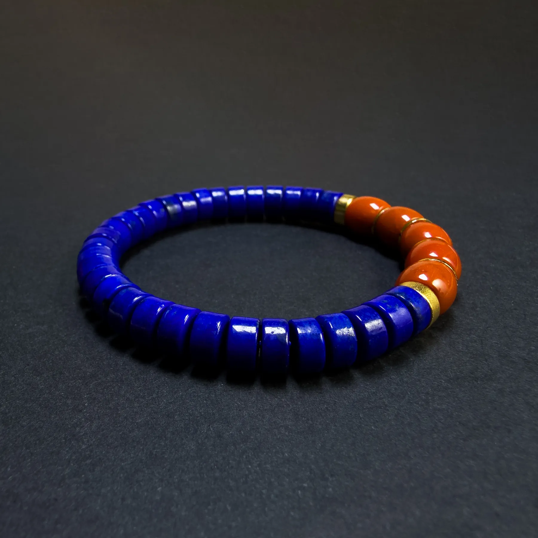 Side angle of royal-blue lapis bracelet with clustered orange-red beads