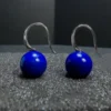 Close silver hook detail above two round lapis lazuli drop earrings