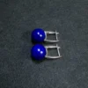 Side view of silver U shaped earrings with polished lapis lazuli beads
