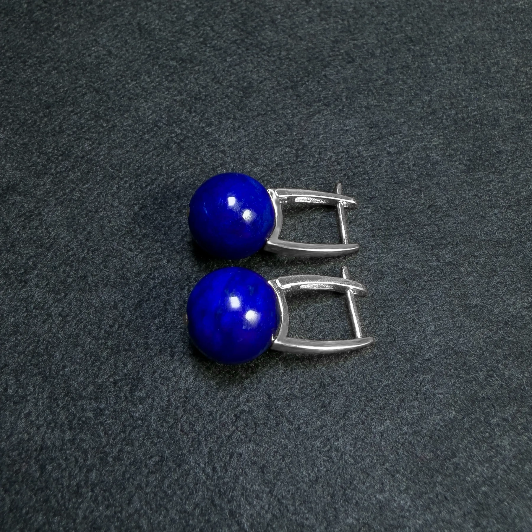 Side view of silver U shaped earrings with polished lapis lazuli beads