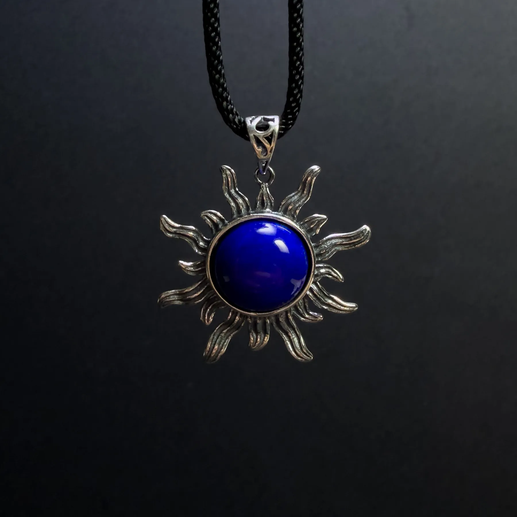 Sterling silver lapis lazuli sun pendant suspended on a black cord