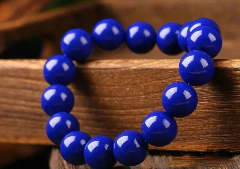Bright blue round bead bracelet resting on stacked wood