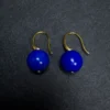 Paired untreated lapis lazuli earrings arranged side by side on dark fabric