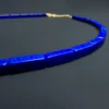 Close low-angle view of untreated rectangular lapis lazuli beads on black