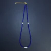 Blue bead necklace layout with side pearls and gold-toned extender