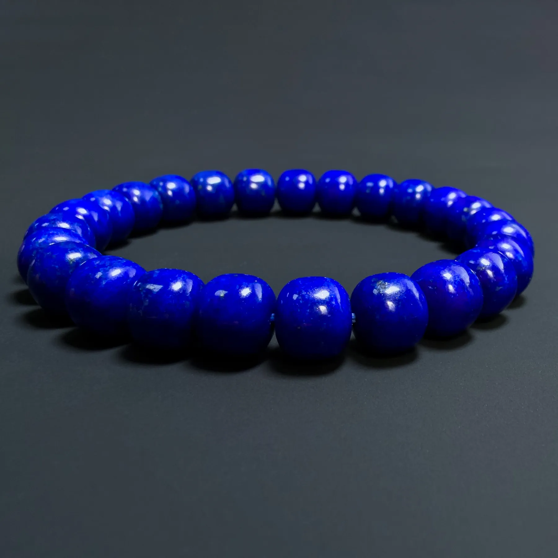 Side view of polished blue lapis barrel beads on elastic cord