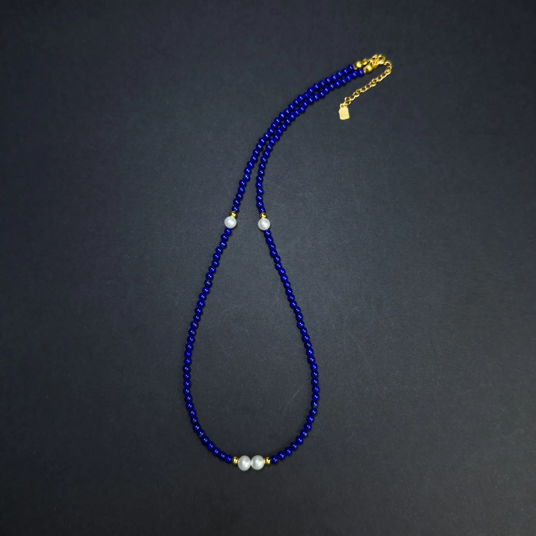 Long flat-lay view of blue lapis lazuli beaded necklace