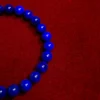 Close-up of curved rows of glossy blue lapis lazuli beads against red fabric
