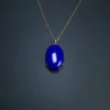 Full view of oval lapis pendant displayed with gold-toned chain